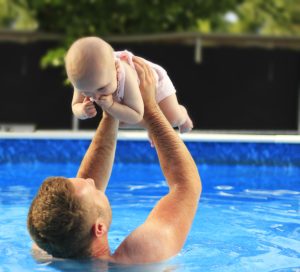 father and child swimming in a pool